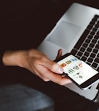 person holding smartphone and laptop