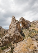 brown land formation under cloudy sky