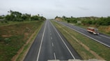 A highway stretching through a rural landscape with a truck in the distance.