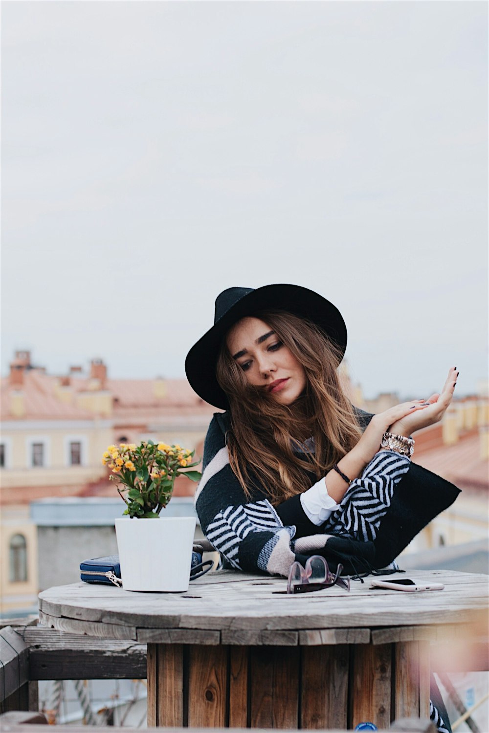 woman sitting beside spool table outdoors under clear blue sky