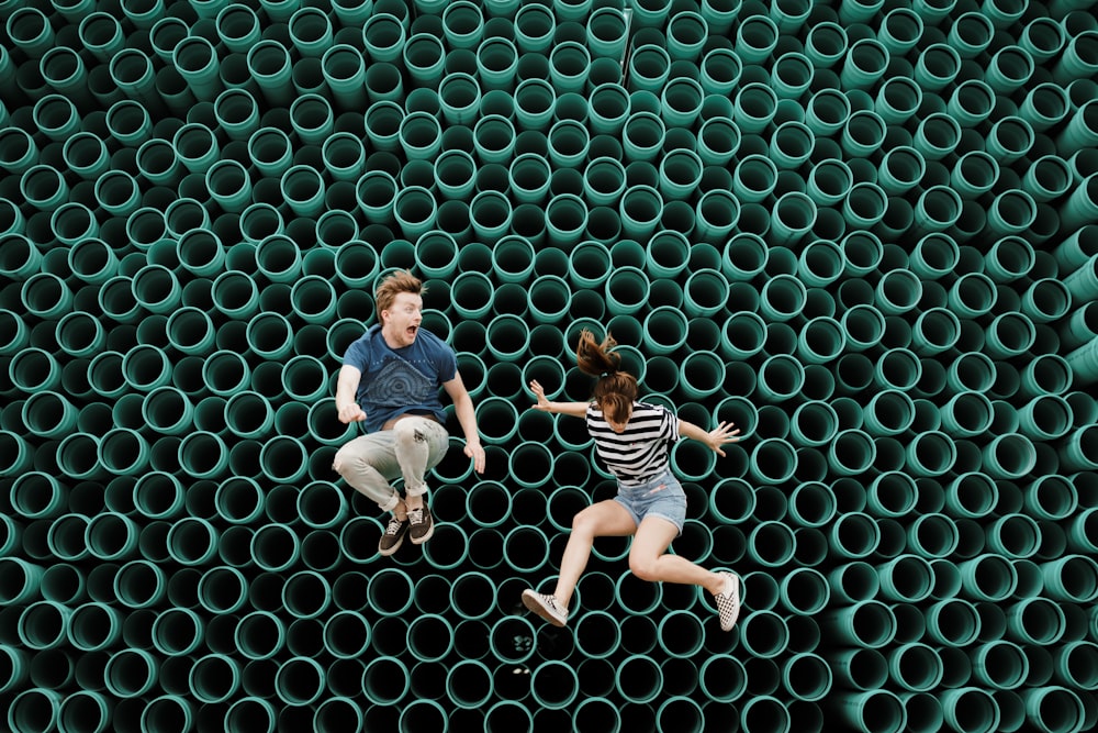 튜브 벽 앞에서 점프하는 남자와 여자의 미니멀리스트 사진