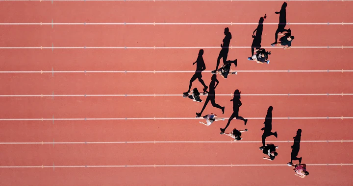 Corredores em raias de pista de atletismo vistos de cima