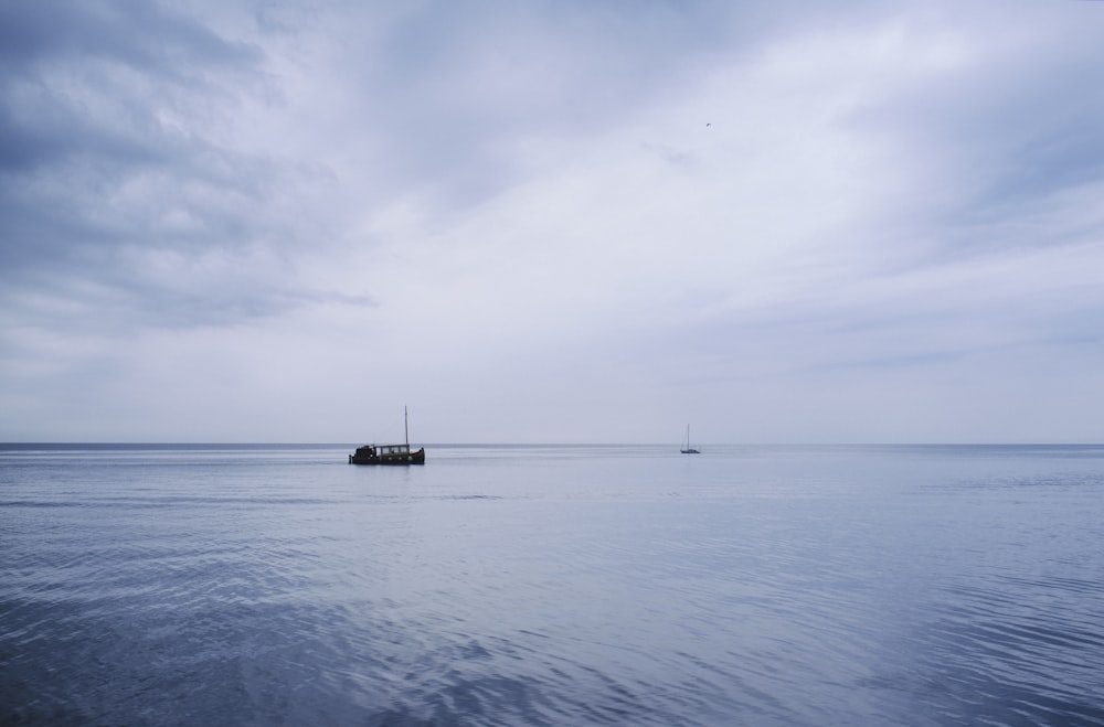 boat on sea under white clouds during daytime