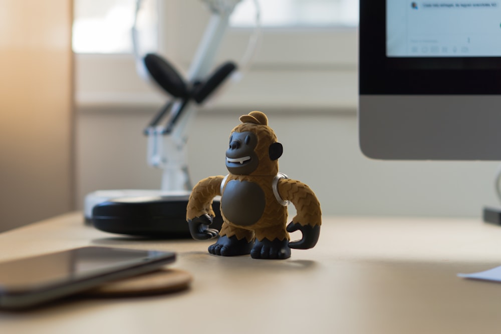 brown monkey toy near black smartphone