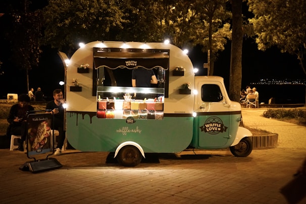 The colorful Waffles & Heaven food truck parked at a lively festival with happy customers enjoying their treats