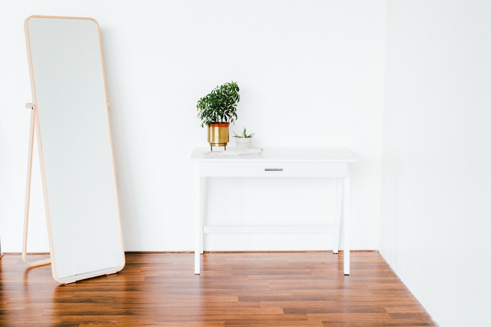 white wooden side table beside white wall