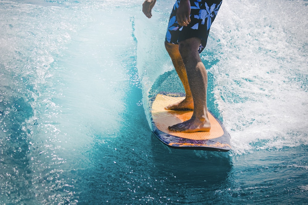 hombre montando ola con tabla de surf naranja