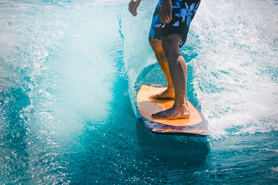 man riding wave with orange surfboard, Wake Skate
