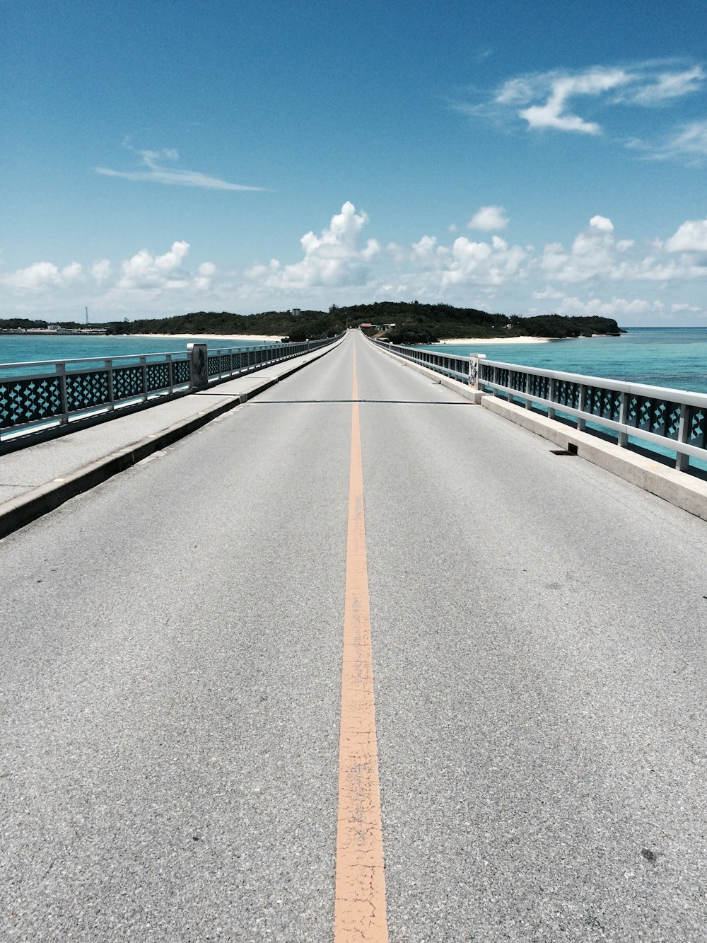 asphalt road near mountain under blue and white cloudy sky