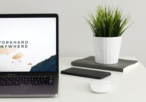 MacBook Pro near green potted plant on table