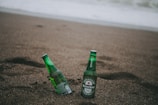 two green Heineken bottles on gray soil