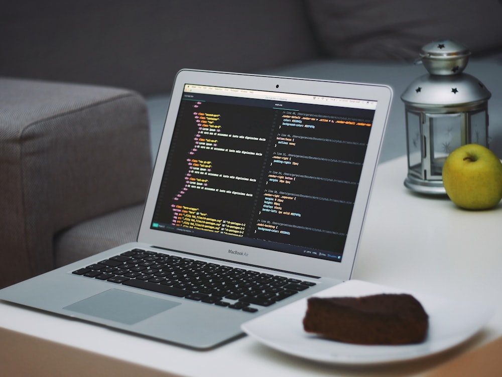 turned on MacBook Air beside saucer with cake on table