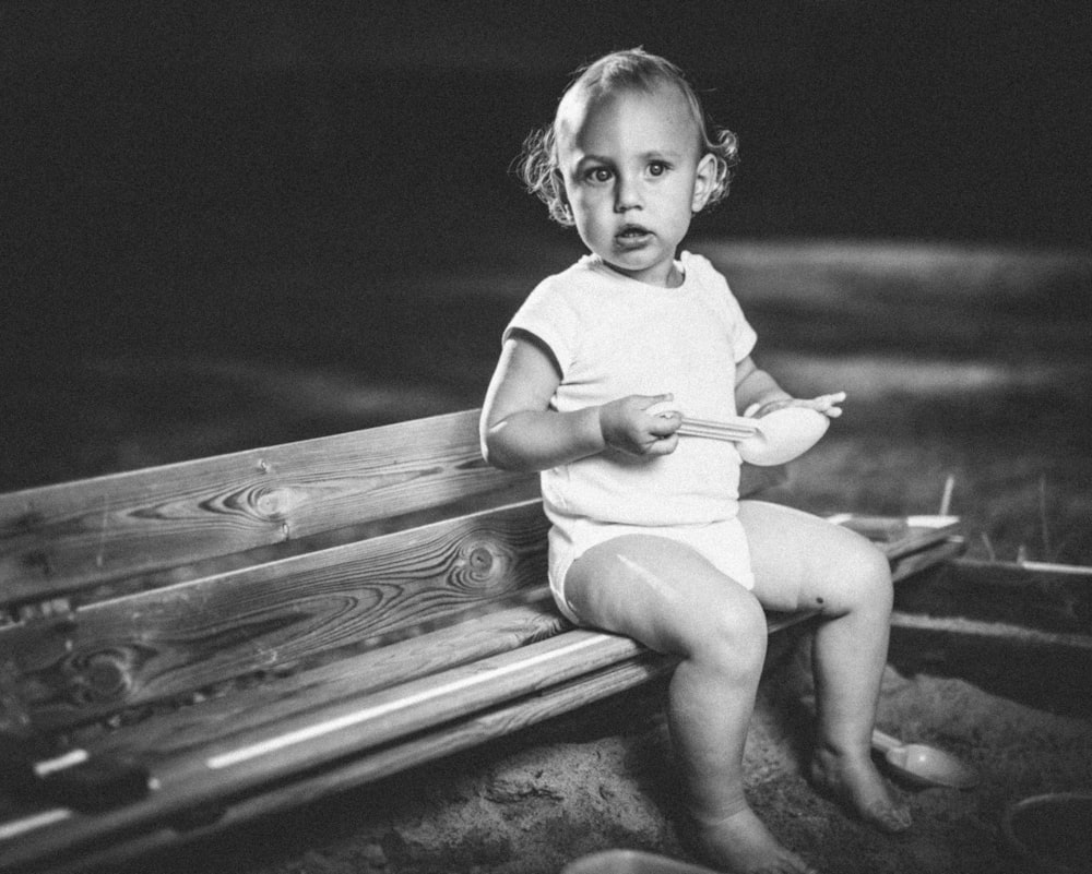 벤치에 앉아있는 유아의 회색조 사진