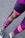 A person is wearing colorful athletic leggings featuring a mix of purple, pink, and yellow patterns and text. The lower legs are visible, along with black and white sneakers standing on an asphalt surface.