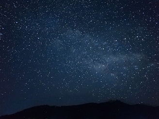 the night sky is filled with stars above a mountain