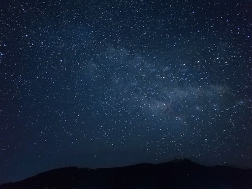 the night sky is filled with stars above a mountain