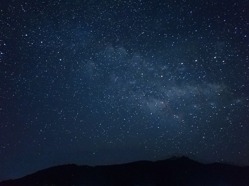 the night sky is filled with stars above a mountain