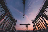 A panoramic view of a large industrial steel structure under construction at sunset.