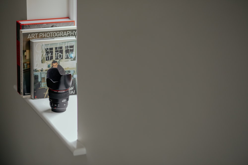 uma câmera sentada em cima de uma prateleira ao lado de um livro