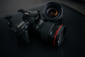 black Canon DSLR camera beside camera lens