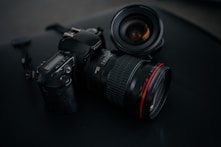 black Canon DSLR camera beside camera lens