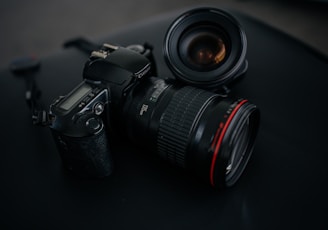 black Canon DSLR camera beside camera lens