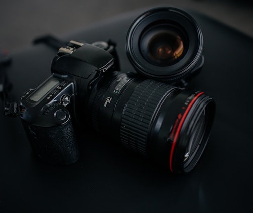 black Canon DSLR camera beside camera lens