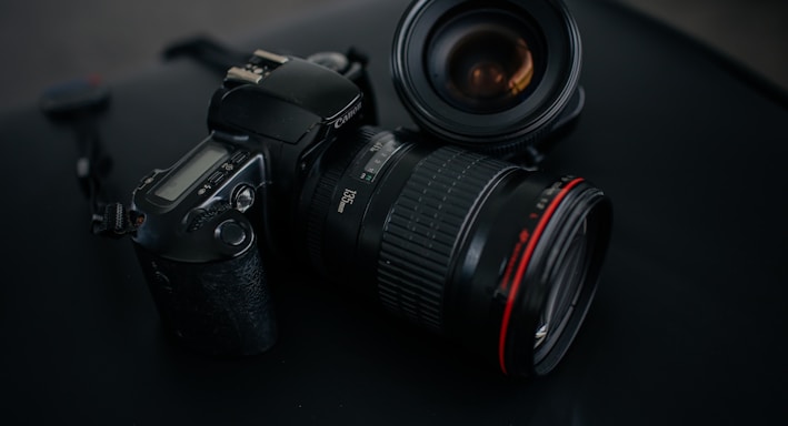 black Canon DSLR camera beside camera lens