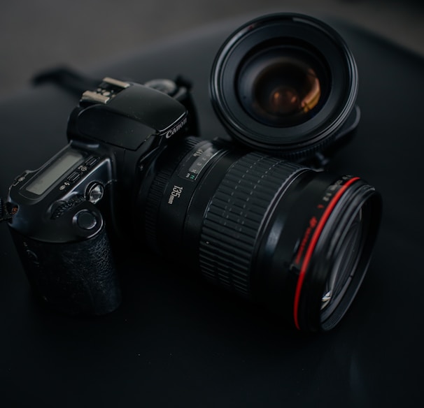 black Canon DSLR camera beside camera lens