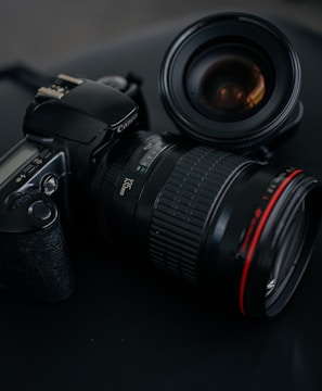 black Canon DSLR camera beside camera lens