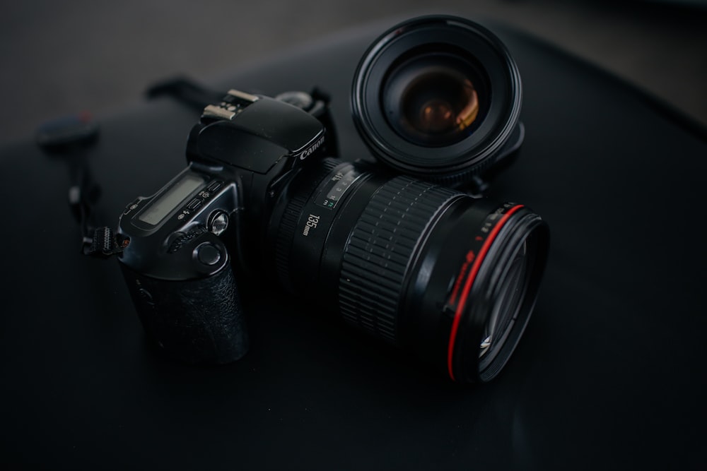 black Canon DSLR camera beside camera lens