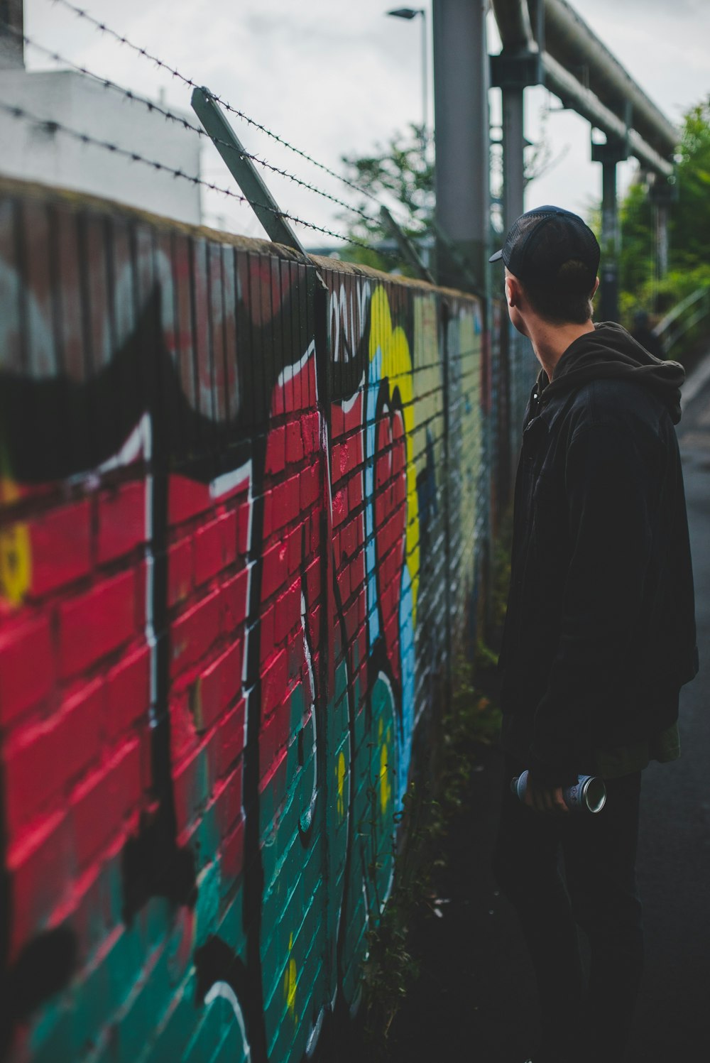 man standing next to concrete fence holding can