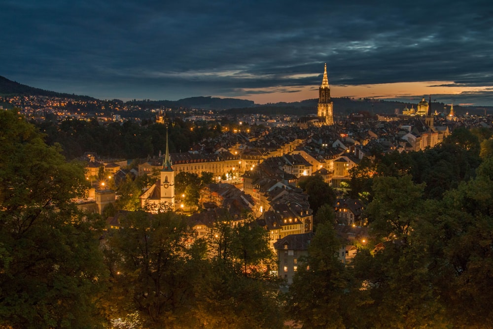 a city lit up at night with a church steeple in the background