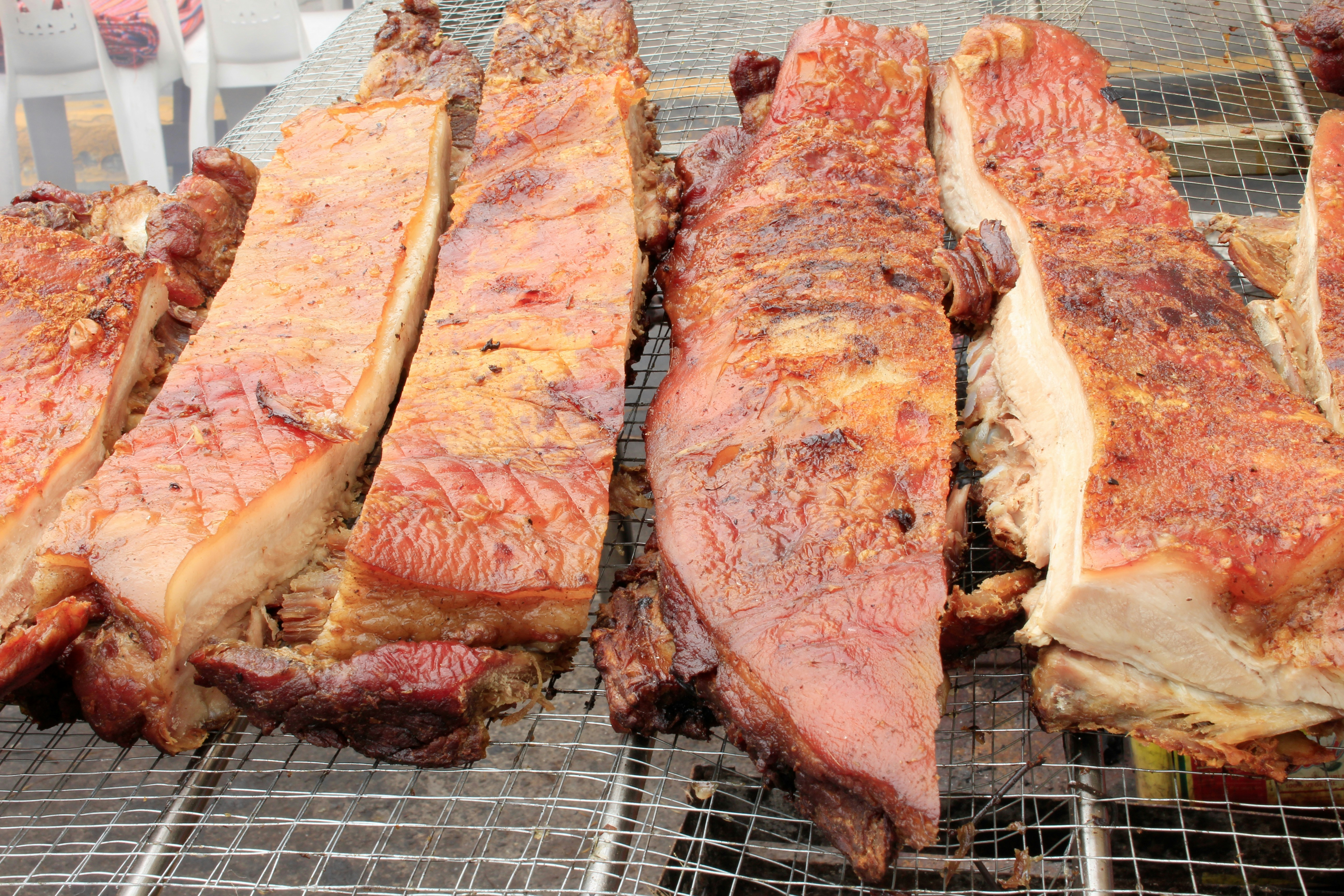 Close-up of crispy lechon pork belly with golden crackling skin, warm amber grill light, dark rustic background