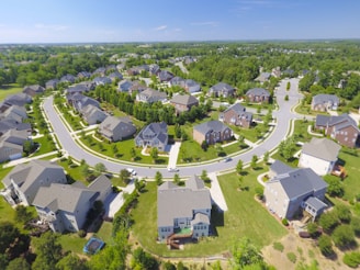 Aerial shot of a modern suburban home with a well-manicured lawn and surrounding neighborhood.
