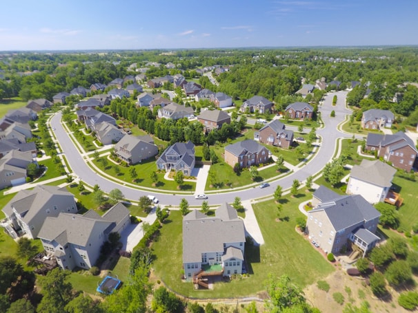 Aerial shot of a modern suburban home with a well-manicured lawn and surrounding neighborhood.