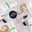 A flat lay of beauty and fashion items on a marble surface, including a tube of Rodan + Fields Soothe gentle cream wash, a container of NARS product, a MAC lipstick with the cap off showing a pink shade, a gold chain bracelet, a gold wristwatch, a pair of small earrings, and two thin gold rings.