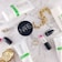 A flat lay of beauty and fashion items on a marble surface, including a tube of Rodan + Fields Soothe gentle cream wash, a container of NARS product, a MAC lipstick with the cap off showing a pink shade, a gold chain bracelet, a gold wristwatch, a pair of small earrings, and two thin gold rings.