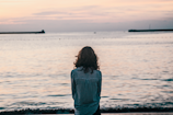 woman in front ocean water under white sky