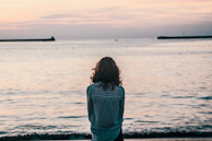 woman in front ocean water under white sky
