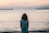 woman in front ocean water under white sky