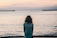 woman in front ocean water under white sky