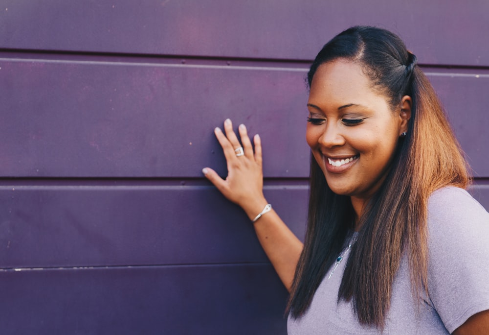 woman wearing purple shirt touching the wall