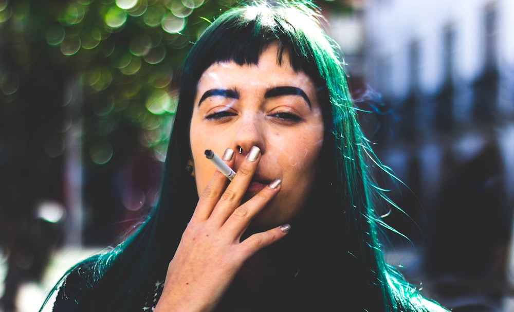 Photographie de mise au point sélective d’une femme fumant une cigarette