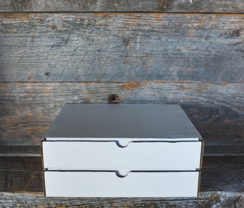 two white cardboard box on wooden shelf