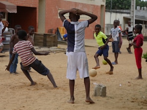 Volunteers helping children learn soccer skills in a park.