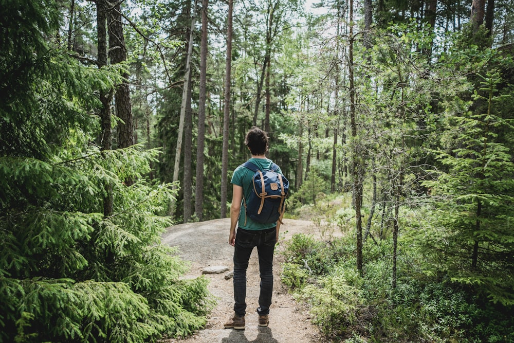 Mann mit blauem Rucksack geht durch Wald