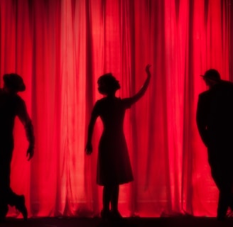 silhouette of three performers on stage