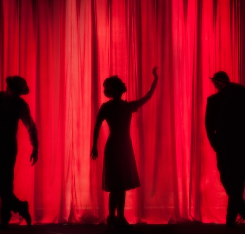 silhouette of three performers on stage