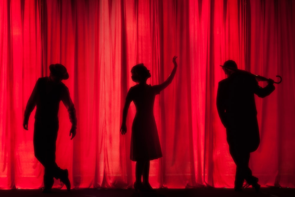 silhouette of three performers on stage